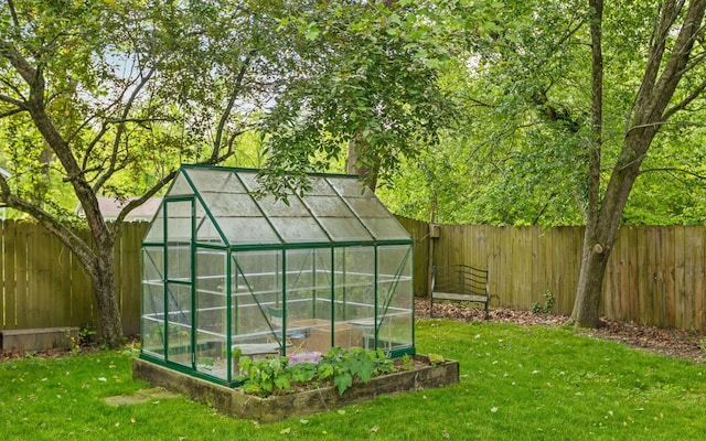 view of greenhouse with a fenced backyard and a yard