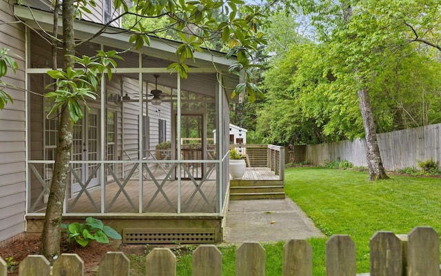 view of yard featuring fence, a ceiling fan, a wooden deck, and a sunroom