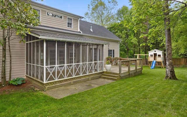 back of house with fence, a sunroom, a deck, a playground, and a yard