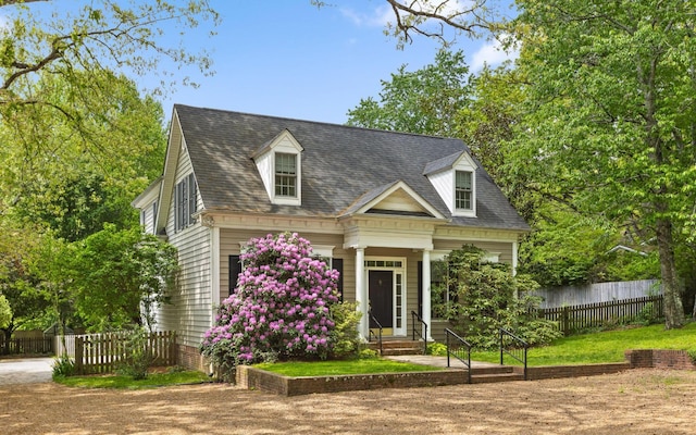 cape cod home featuring fence and a shingled roof
