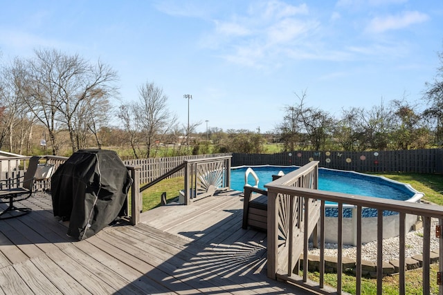 deck with a fenced backyard, a fenced in pool, and area for grilling