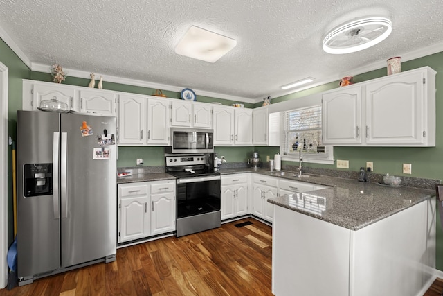 kitchen featuring crown molding, stainless steel appliances, a sink, white cabinets, and a peninsula