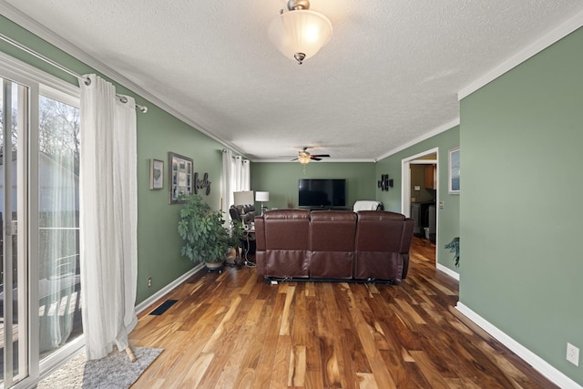 living area with crown molding, a ceiling fan, wood finished floors, a textured ceiling, and baseboards