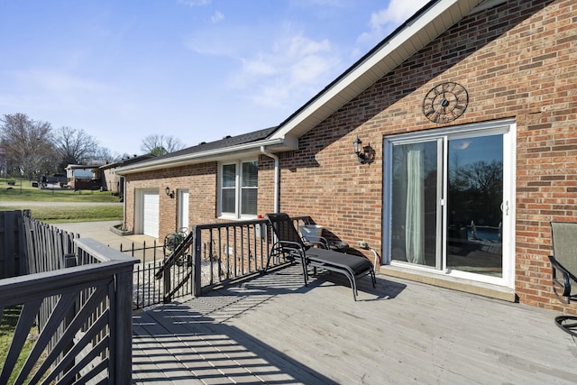 wooden terrace featuring concrete driveway, a garage, and fence