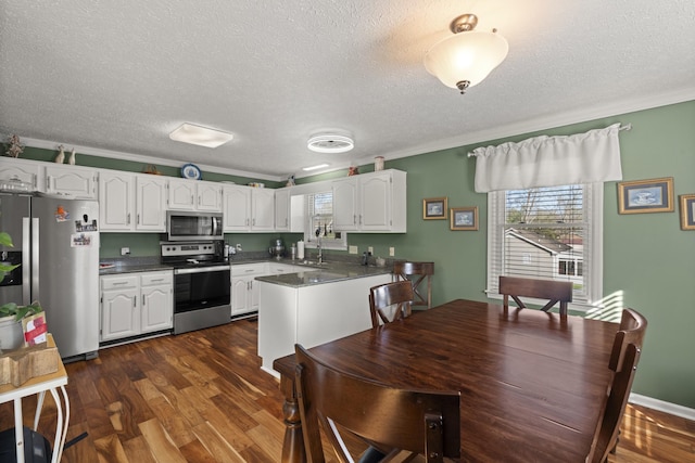 kitchen with dark wood-type flooring, white cabinetry, stainless steel appliances, and dark countertops