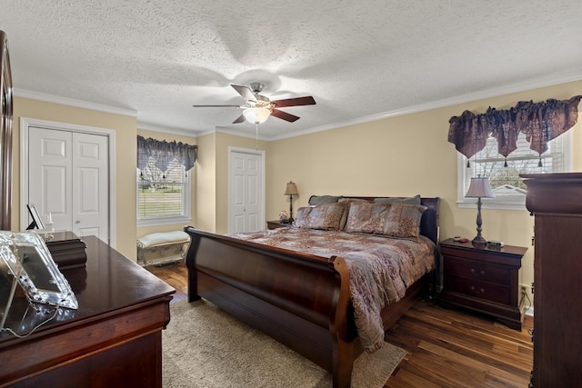 bedroom featuring ornamental molding, two closets, and dark wood finished floors