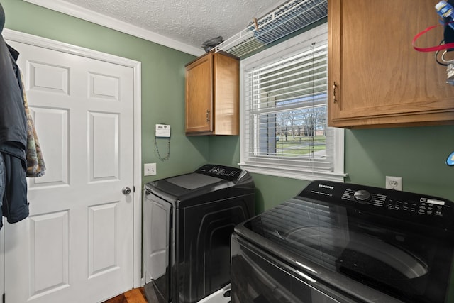 clothes washing area featuring cabinet space, a textured ceiling, crown molding, and washer and dryer