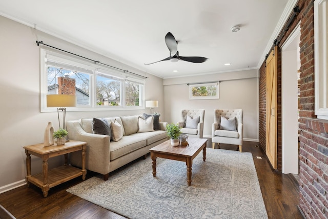 living room featuring baseboards, a barn door, ornamental molding, and dark wood finished floors