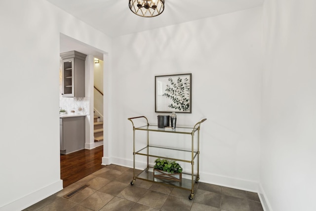 hall featuring baseboards, visible vents, and stairway