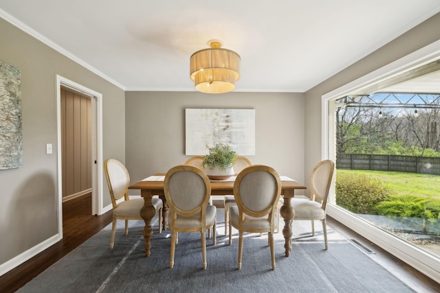dining space with baseboards, visible vents, crown molding, and wood finished floors