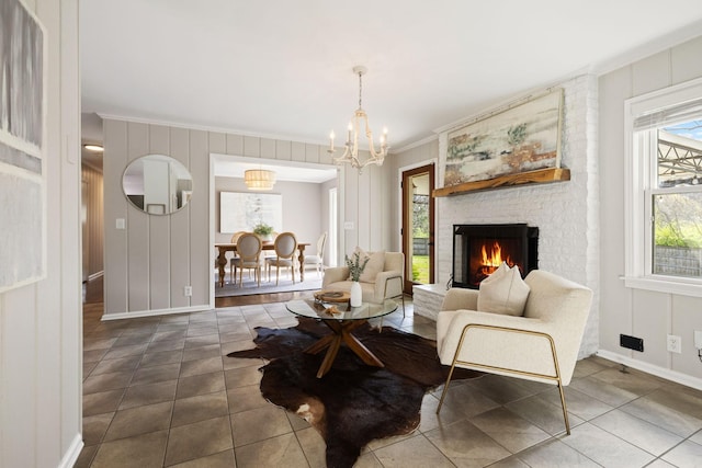 living area with a notable chandelier, crown molding, a fireplace, tile patterned flooring, and baseboards