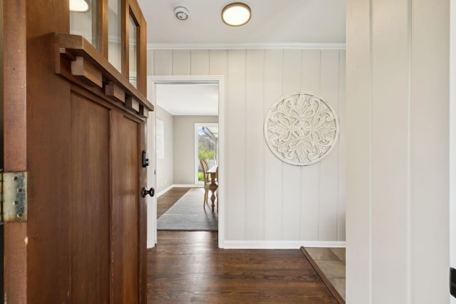 foyer entrance featuring baseboards, crown molding, and dark wood finished floors