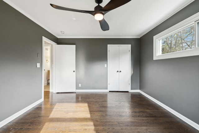 unfurnished bedroom with a closet, ornamental molding, baseboards, and wood finished floors