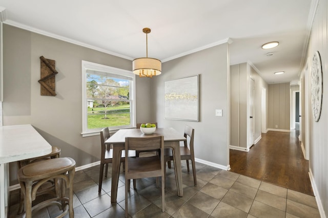 dining room featuring baseboards, tile patterned flooring, and crown molding
