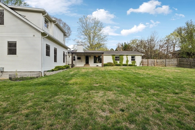 back of property featuring a lawn, a chimney, and fence