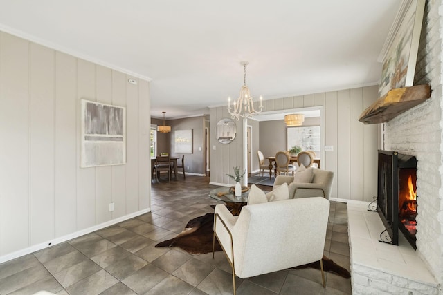 living room featuring an inviting chandelier, a brick fireplace, ornamental molding, and baseboards