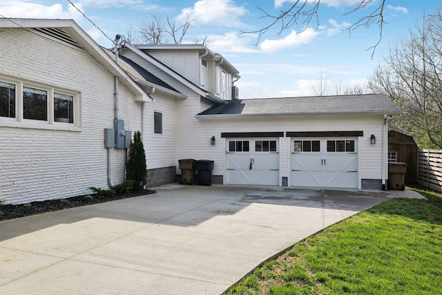 view of side of home with board and batten siding, a garage, concrete driveway, and fence