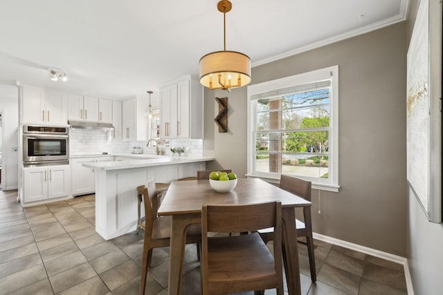 dining room with light tile patterned floors, crown molding, and baseboards