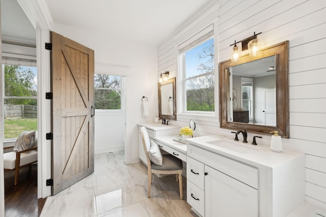 bathroom featuring marble finish floor, vanity, wood walls, and connected bathroom