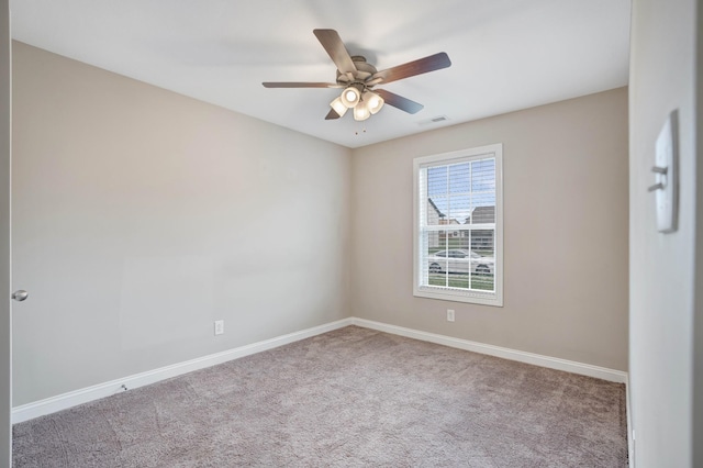 carpeted spare room featuring baseboards, visible vents, and ceiling fan