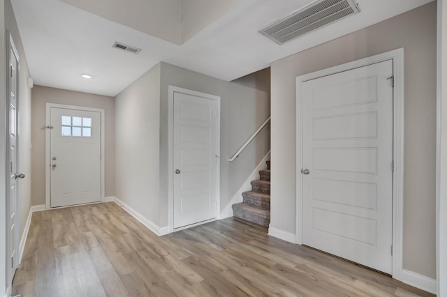 foyer featuring light wood-type flooring, baseboards, and visible vents