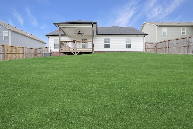 rear view of property featuring a fenced backyard, a deck, a ceiling fan, central AC, and a lawn