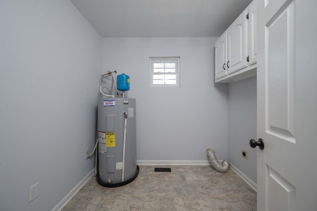 washroom with baseboards, cabinet space, visible vents, and electric water heater