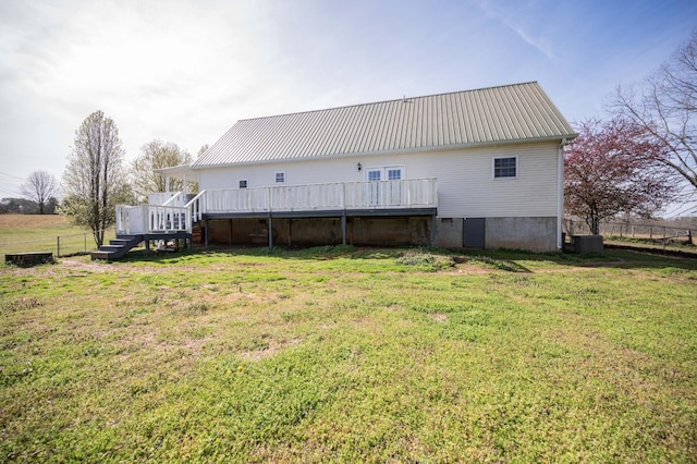 rear view of property with a lawn, metal roof, fence, and a wooden deck