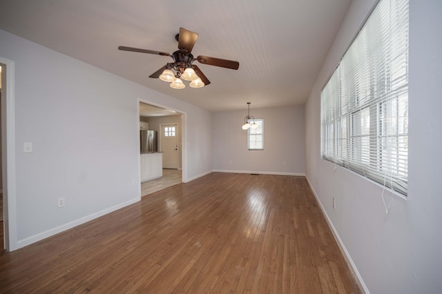 empty room featuring baseboards, ceiling fan, and light wood-style flooring