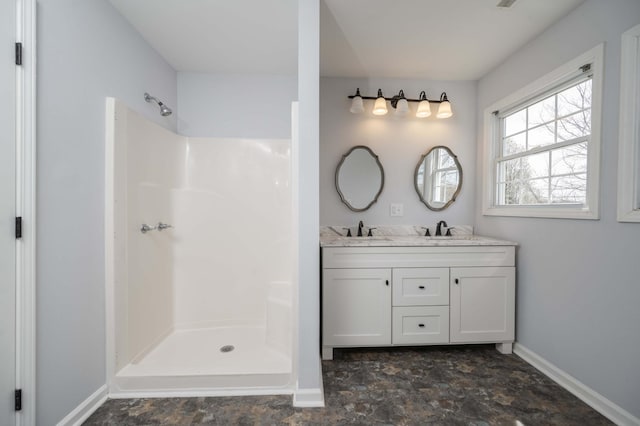 bathroom featuring double vanity, a sink, baseboards, and a shower stall