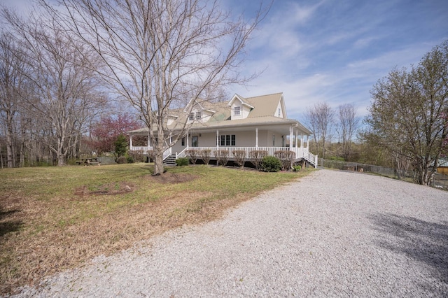 farmhouse with a front lawn, gravel driveway, and covered porch