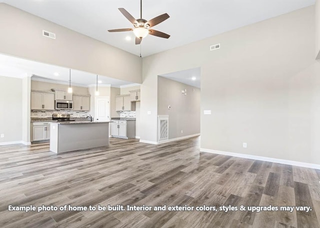 unfurnished living room featuring baseboards, visible vents, and ceiling fan