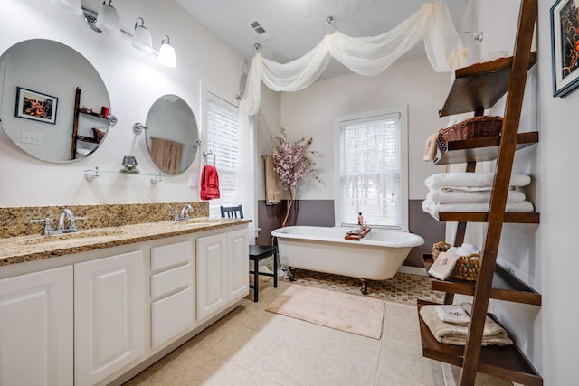 bathroom with double vanity, a sink, tile patterned flooring, and a soaking tub