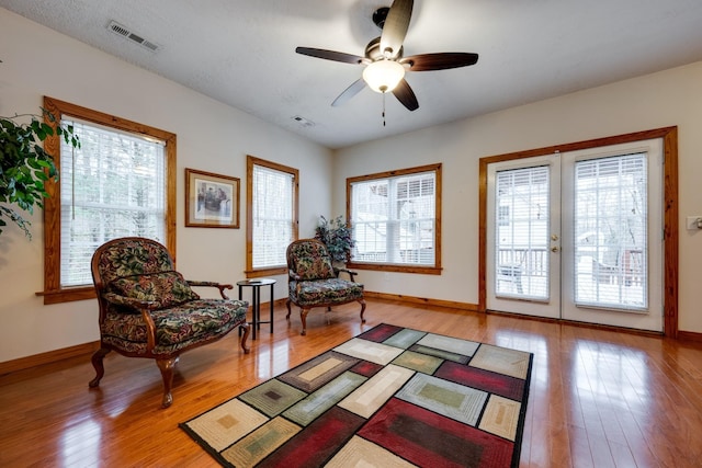 sitting room with hardwood / wood-style floors, ceiling fan, visible vents, and french doors