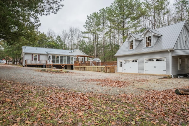 exterior space with metal roof, a garage, gravel driveway, and a deck