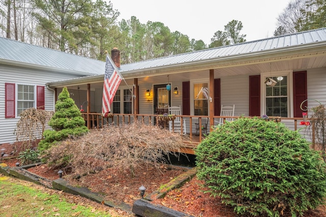 view of front of home featuring a chimney, metal roof, and a porch