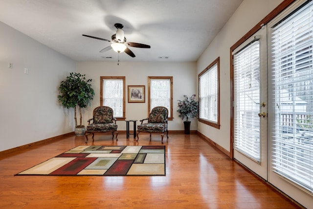 living area featuring a wealth of natural light, wood finished floors, and a ceiling fan