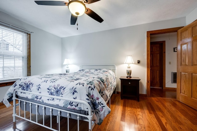 bedroom with baseboards, ceiling fan, hardwood / wood-style flooring, and a textured ceiling