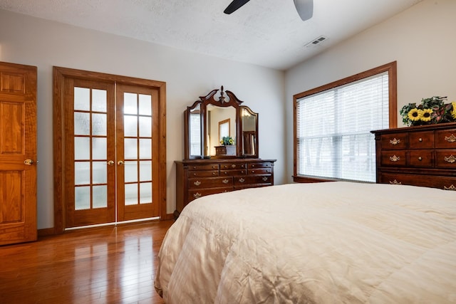 bedroom with french doors, wood-type flooring, a textured ceiling, and visible vents