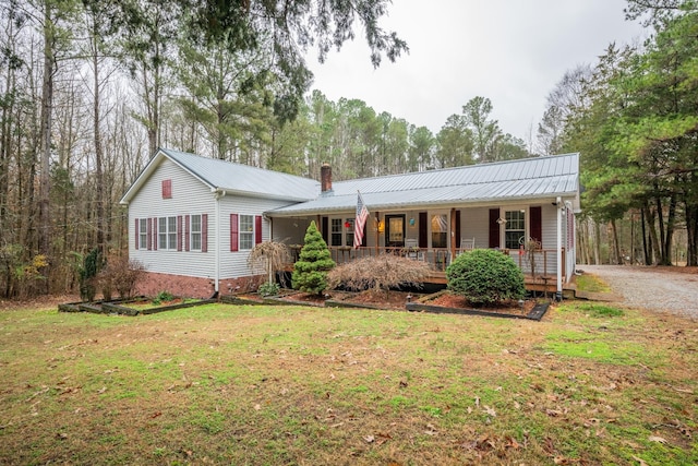 single story home featuring covered porch, a chimney, a front lawn, and metal roof