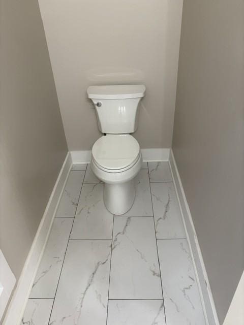 bathroom with baseboards, toilet, and marble finish floor