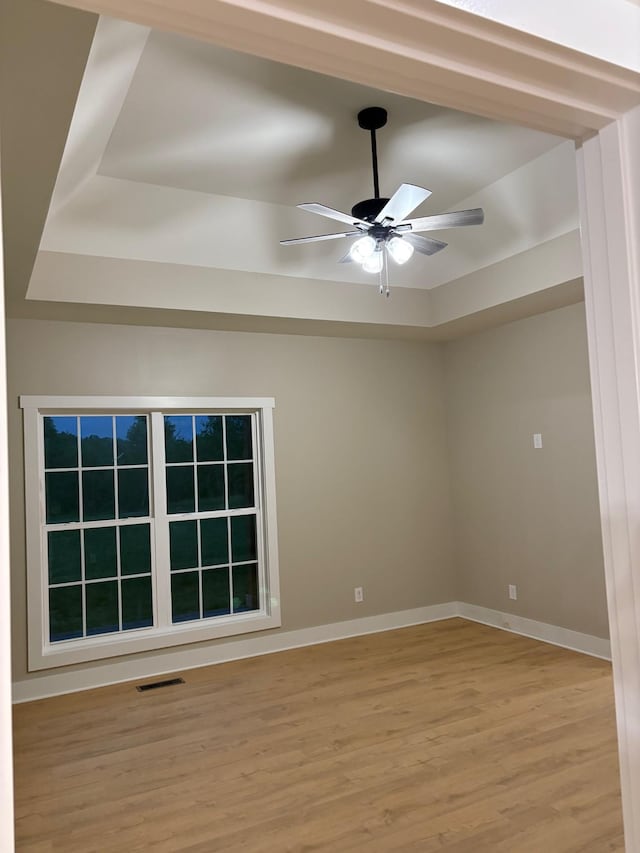 spare room with visible vents, a ceiling fan, light wood finished floors, and baseboards