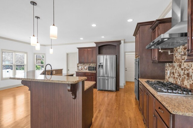 2726 Wynthrope Hall Dr, Murfreesboro, TN 37129 - kitchen featuring stainless steel appliances, wall chimney range hood, a breakfast bar area, decorative backsplash, and light wood-style floors