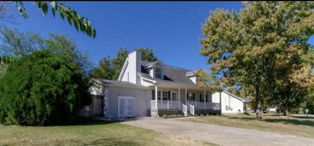 cape cod-style house with covered porch, a chimney, and a front lawn