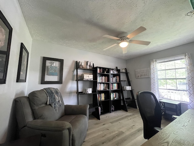 office with a ceiling fan, a textured ceiling, and light wood-type flooring