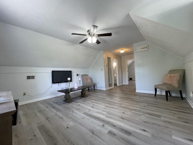 living area with visible vents, wood finished floors, and lofted ceiling