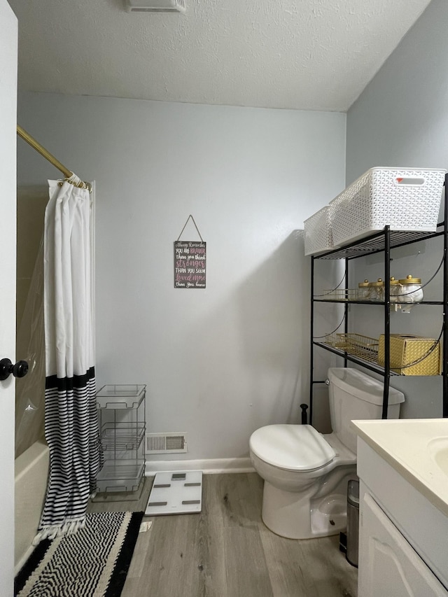 full bathroom with visible vents, vanity, wood finished floors, toilet, and baseboards