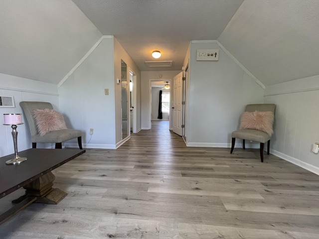 living area featuring wood finished floors, baseboards, and lofted ceiling