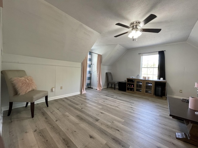 additional living space with a textured ceiling, a ceiling fan, baseboards, wood finished floors, and lofted ceiling