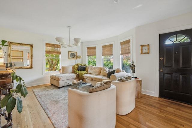 living area with a chandelier, wood-type flooring, and baseboards